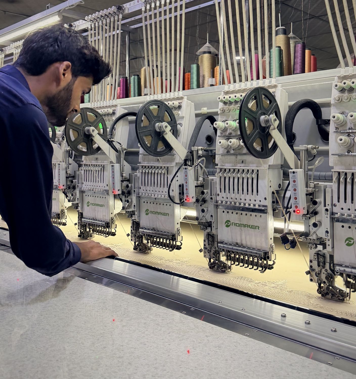 Operator guiding metallic lace embroidery under the heads