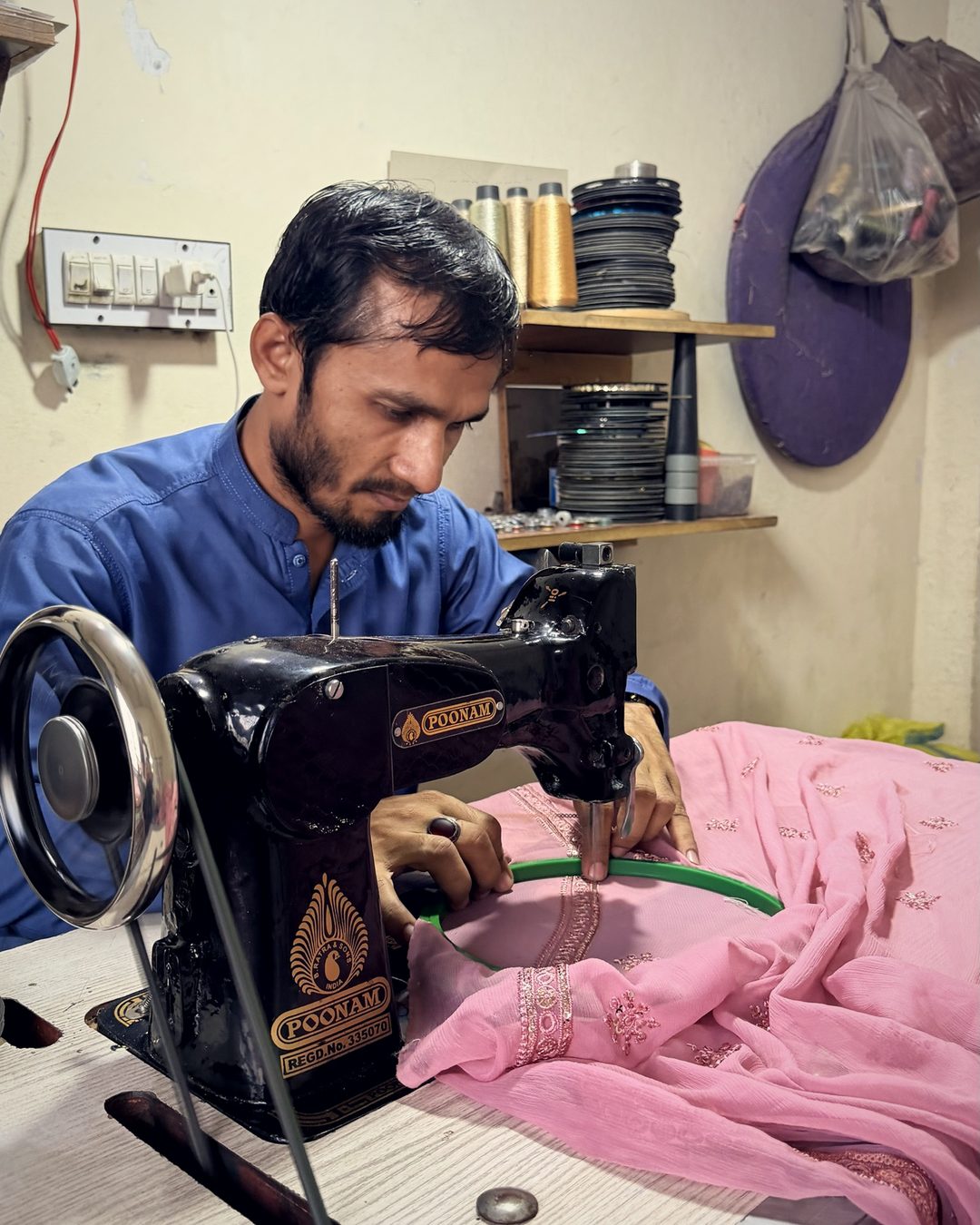 Karigar detailing a pink chiffon neckline on a hand-guided embroidery machine
