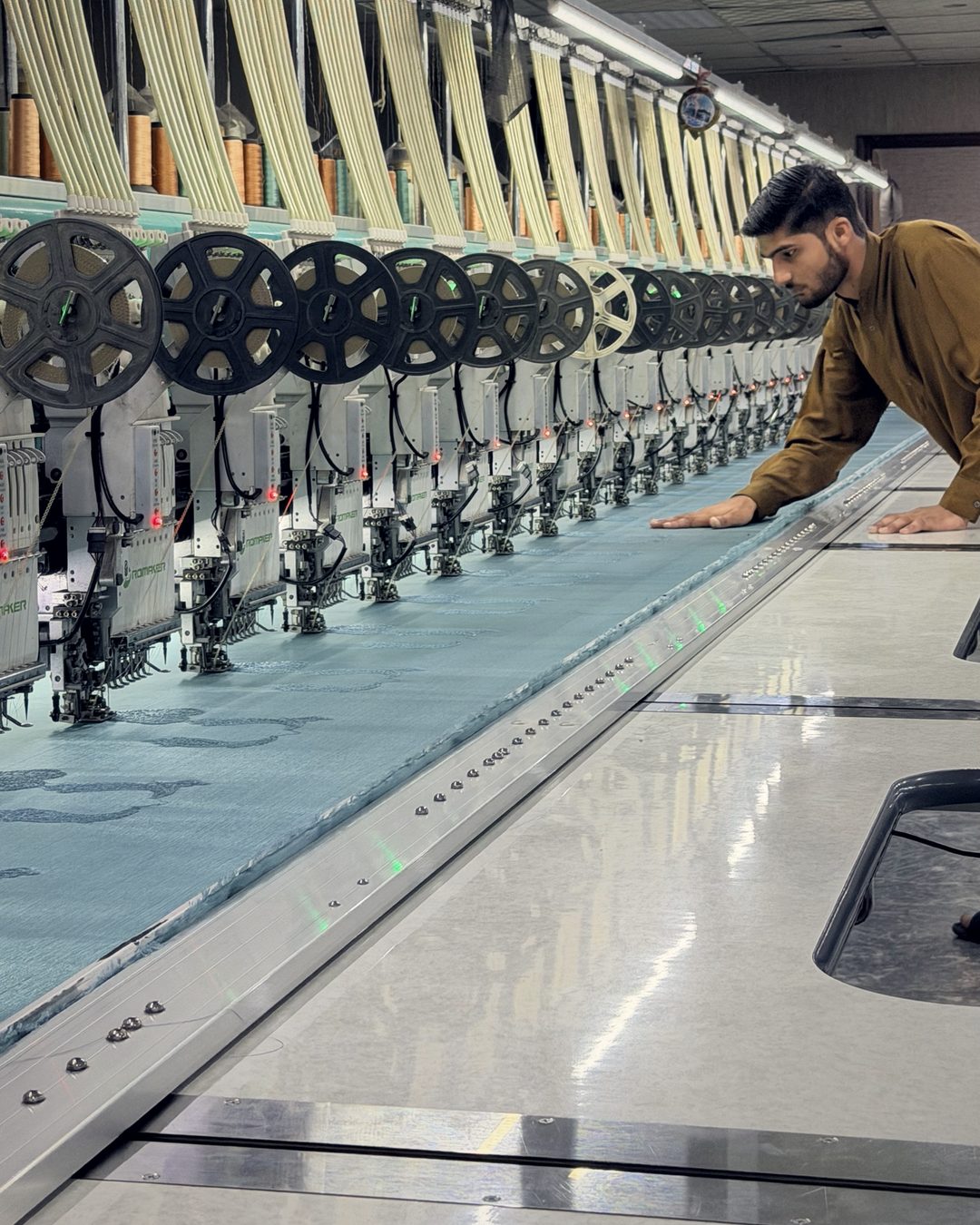 Assistant operator smoothing fabric on a long multi-head machine