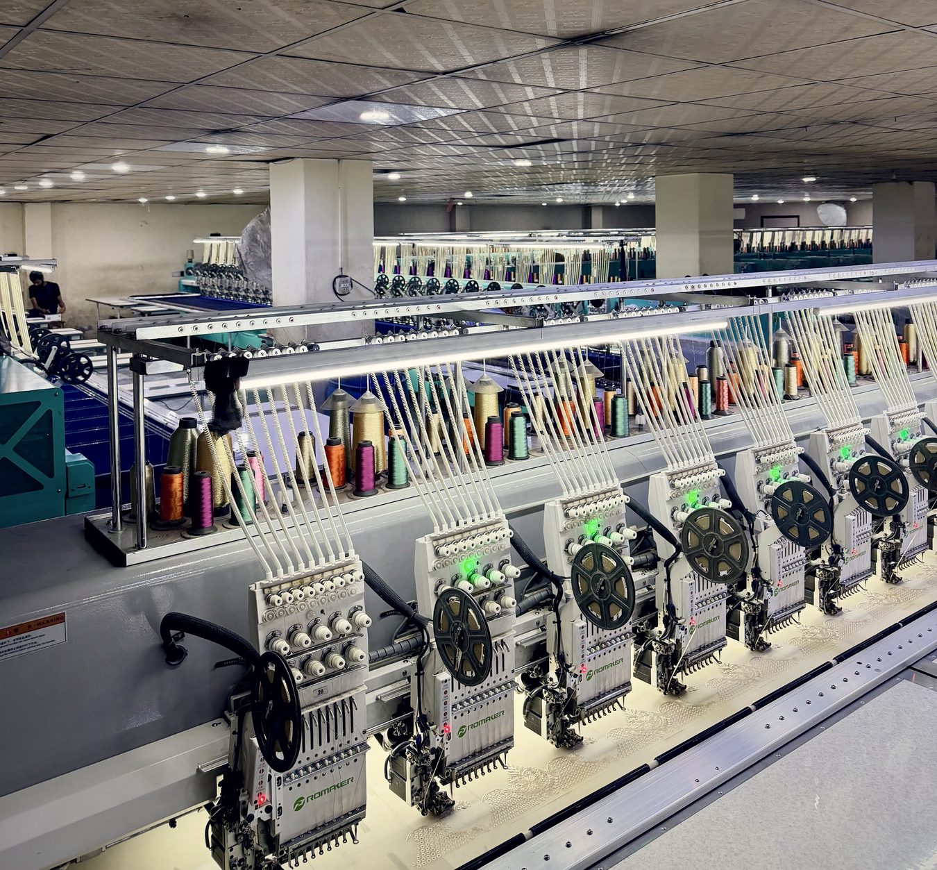 Rows of Promaker multi-head embroidery machines with thread cones and sequin reels