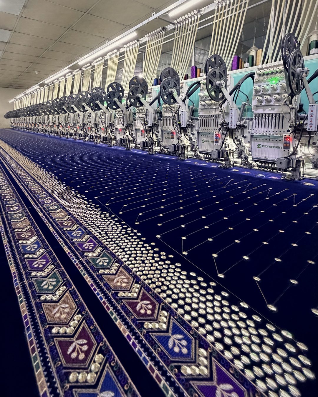 Sequin and thread border running across a long line of embroidery heads on navy velvet