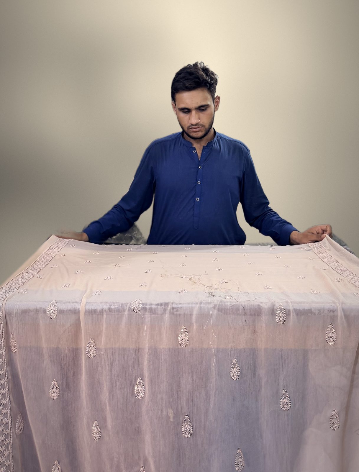 Inspector holding up an embroidered dupatta for final inspection